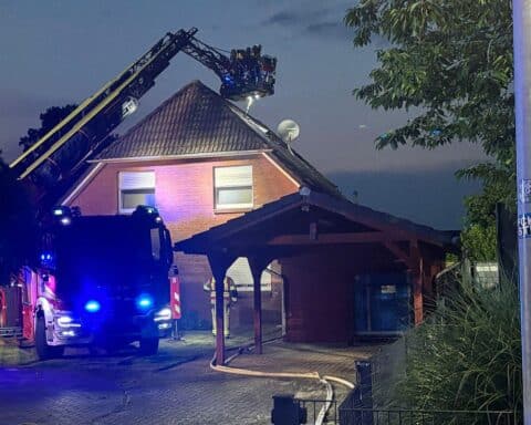 Feuerwehr entfernt Dachpfannen, um Brandursache zu untersuchen und Glutnester zu finden.