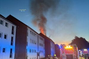 Dachstuhlbrand in Paderborn: Feuerwehr im Einsatz, Rauch und Flammen über dem Gebäude.