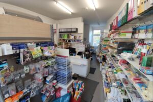 Einzelhandelsumsatz im April gesunken Büroartikelgeschäft mit Kunden, Schreibtischartikeln und besorgten Gesichtern, symbolisiert sinkenden Einzelhandelsumsatz.