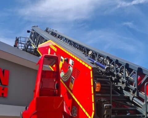 Einsatzkräfte der Feuerwehr löschen Brand in Gewerbeobjekt, während Rauch und Schäden sichtbar sind.