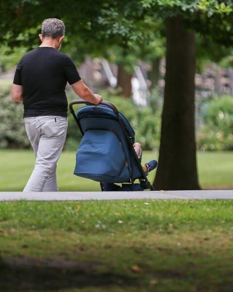 Mann hält Kind, symbolisiert Elternzeit und die Diskussion um Elterngeldanpassungen.