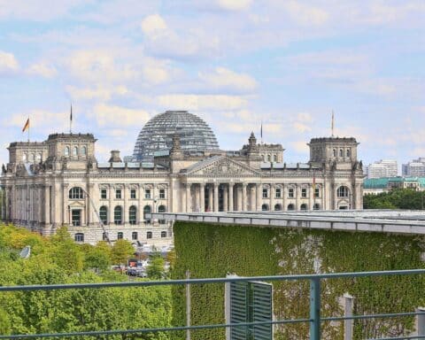 Reichstagsgebäude mit Parlamentariern, die über wichtige Reformen während der Sommerpause diskutieren.