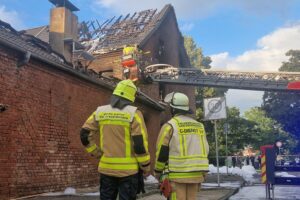 Feuerwehr im Einsatz, löschendes Gebäude, dichte Rauchentwicklung, besorgte Anwohner, mutmaßlicher Zimmerbrand.