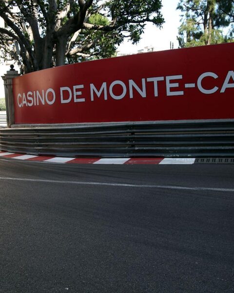 Formel-1-Rennwagen auf der historischen Strecke in Monaco, umgeben von typischer Stadtarchitektur.