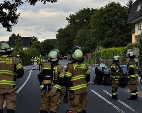 Drei beschädigte Fahrzeuge, Feuerwehr vor Ort, Einsatzkräfte und medizinische Versorgung auf der Straße.