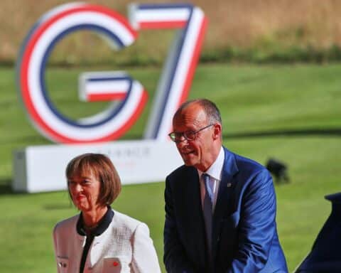 Friedrich Merz und Charlotte Merz beim G7-Gipfel in Évian-les-Bains, umgeben von internationalen Staatschefs.