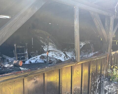 Feuerwehr löscht Garagenbrand, schützt angrenzendes Wohnhaus, Einsatzkräfte bei Aufräumarbeiten.