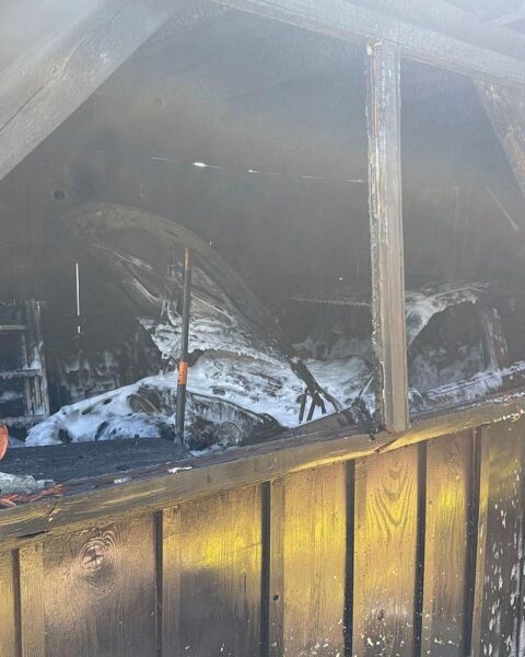 Feuerwehr löscht Garagenbrand, schützt angrenzendes Wohnhaus, Einsatzkräfte bei Aufräumarbeiten.