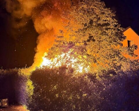 Einsatz der Feuerwehr Neuss bei Gartenhausbrand, mit Flammen und Feuerwehrfahrzeugen im Einsatz.
