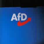 AfD-Logo vor einem Hintergrund, der staatliche Überwachung und gesellschaftliche Spannungen symbolisiert.