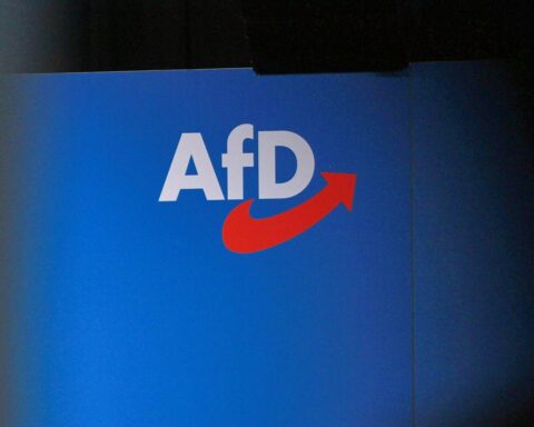 AfD-Logo vor einem Hintergrund, der staatliche Überwachung und gesellschaftliche Spannungen symbolisiert.