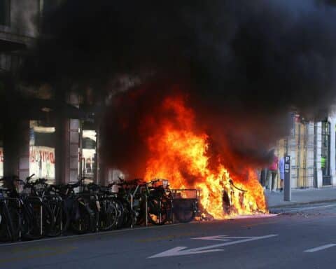 Protestierende in Genf, brennendes Auto, vermummte Demonstranten, Spannung und Gewalt am G7-Gipfel.