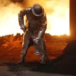 Frau in Arbeitskleidung diskutiert mit Gewerkschaftsvertretern über Industriepolitik und soziale Gerechtigkeit.