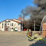 Großbrand im Feuerwehrhaus Unterensingen: Zerstörtes Gebäude, Rettungskräfte im Einsatz, flammende Rückstände.