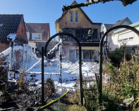 Brandstelle mit Feuerwehr und Rauchentwicklung, beschädigtes Wohnhaus, Einsatzkräfte im Löscheinsatz.