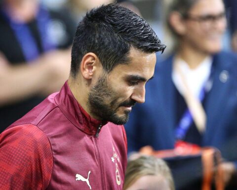Ilkay Gündogan in Fußballtrikot, nachdenklich, mit kritischem Gesichtsausdruck, im Stadionumfeld.