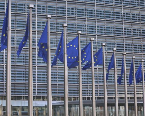 EU-Fahnen symbolisieren Debatte über Arbeiterrechte im Kontext neuer Unternehmensrechtsform.