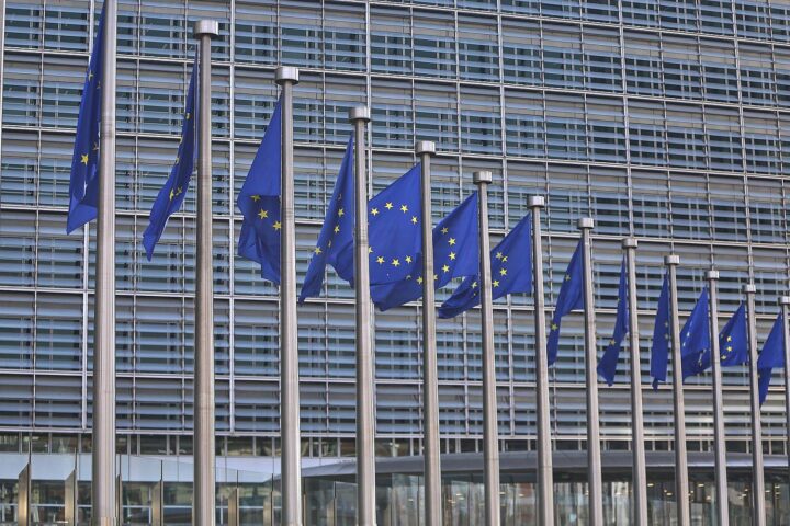 EU-Fahnen symbolisieren Debatte über Arbeiterrechte im Kontext neuer Unternehmensrechtsform.