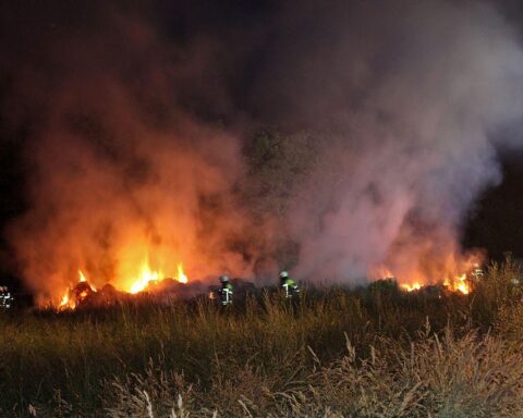 Flammen züngeln aus einer Heumiete; Feuerwehr bekämpft Brand in abgelegener Umgebung.