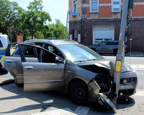 Ein zerstörtes Auto, eine beschädigte Ampel und Einsatzkräfte an einem Unfallort.