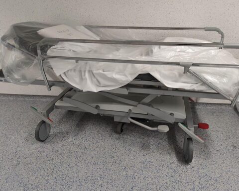 Ein Krankenhauszimmer mit einem Patienten, der in einem Bett liegt, umgeben von medizinischen Geräten.