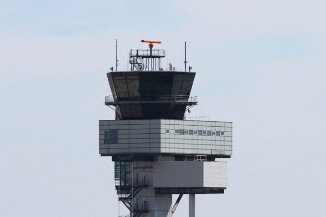 Flughafentower vor dem Hintergrund steigender Treibstoffpreise und Gewinnrückgang der Luftfahrtbranche.