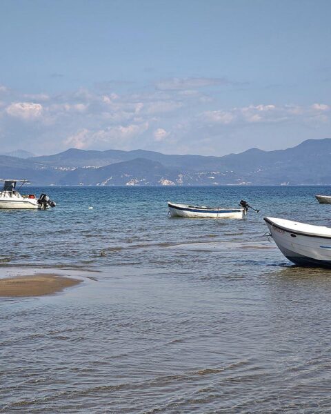Boote am malerischen Strand von Korfu symbolisieren unerschwinglichen Urlaub für viele Menschen 2025.