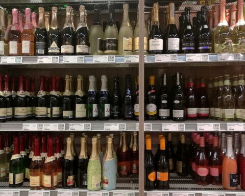 Eine handliche Flasche Sekt auf einem eleganten Tisch mit Gläsern im Hintergrund.