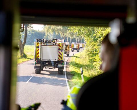 Gruppennahaufnahme von Feuerwehrleuten und DRK-Helfern bei der Großübung mit Zelten und Einsatzfahrzeugen.