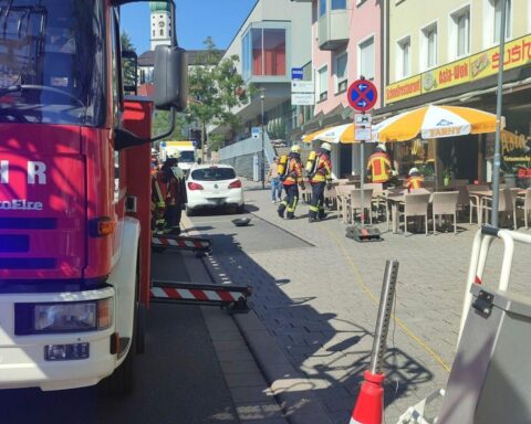 Feuerwehrlöscharbeiten in Restaurantküche, Rauchentwicklung und Einsatzfahrzeuge sichtbar. Sicherheit im Vordergrund.
