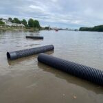 Kunststoffrohre schwimmen im Rhein, nach Regenfällen vom Salzbach geschwemmt, Einsatzkräfte bergen sie.