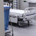 Protestierende Menschen vor einem Krankenhaus, Schilder gegen Pflegereform und soziale Ungerechtigkeit.
