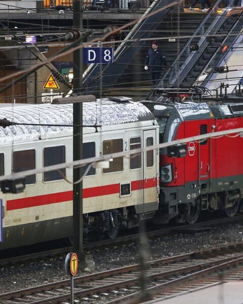 Ein Mann holt Schuh von Gleis, Zugbegleiter stoppt Abfahrt, Gefahr des Gleisaufenthalts.
