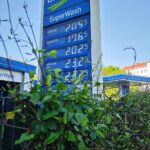 Tankstelle mit Zapfsäulen, Benzinpreisanzeige und Kunden, die tanken.