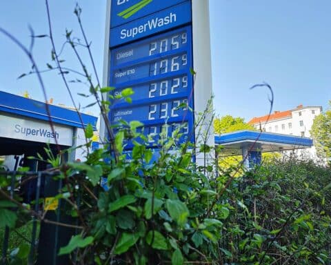 Tankstelle mit Zapfsäulen, Benzinpreisanzeige und Kunden, die tanken.