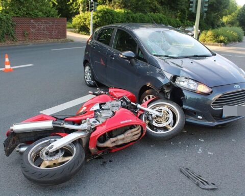 Motorradfahrer und Auto nach Unfall auf Kölner Straße, Polizei und Rettungsdienst vor Ort.