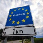 Grenzübergang Deutschland-Niederlande mit Warteschlangen, symbolisiert Konflikt über Grenzkontrollen und Migration.