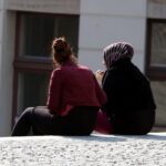 Zwei Frauen, eine mit Kopftuch und eine ohne, symbolisieren Vielfalt und Integration in Deutschland.