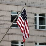 US-Flagge vor dramatischem Hintergrund, symbolisiert Konflikt zwischen USA und Iran im Persischen Golf.