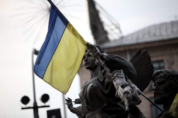 Flagge der Ukraine vor Hintergrund von Zerstörung und Trauer durch die russischen Angriffe.