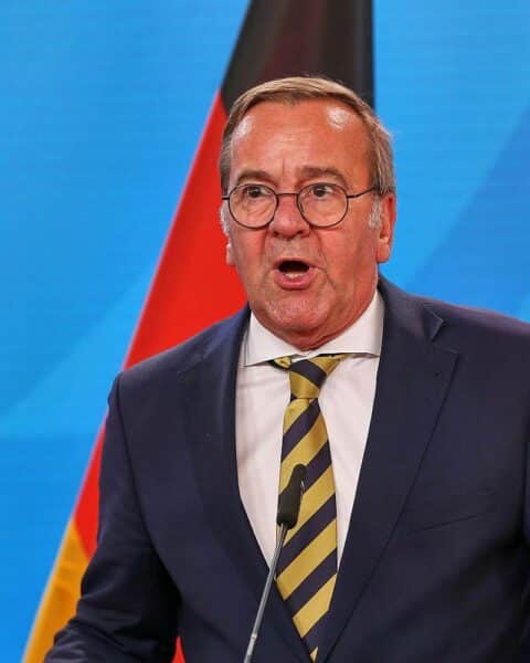 Boris Pistorius am Tisch, diskutierend, mit europäischer Flagge im Hintergrund während Nato-Treffen.