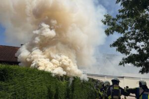 Rauchentwicklung über einem Garagenhof, Feuerwehr im Einsatz, verletzte Personen, gelöscht und kontrolliert.