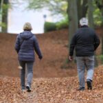 Älteres Paar betrachtet Renteninformation, symbolisiert steigende Rentenbeiträge und demografische Veränderungen.