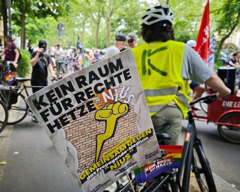 Demonstranten auf Fahrrädern protestieren gegen rechte Medienportale in Kreuzberg, Berlin. Banner und Transparente sichtbar.