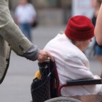 Seniorin im Rollstuhl, die symbolisch für Pflegebedürftigkeit und deren Herausforderungen steht.