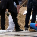 Hochwasser-Helfer füllen Sandsäcke, um Communities auf zukünftige Naturkatastrophen vorzubereiten.