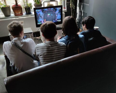 Junge Menschen spielen Videospiele, symbolisieren digitale Freizeit und Herausforderungen im Jugendschutz.