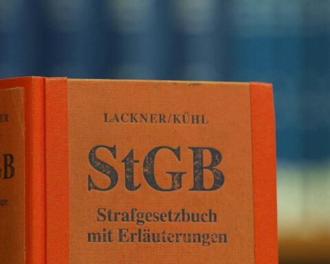 Das Bild zeigt das Strafgesetzbuch in einer Bibliothek, symbolisch für juristische Diskussionen.