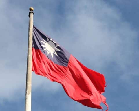 Taiwan-Flagge mit militärischen Aktivitäten und Kampfflugzeugen im Hintergrund, symbolisiert Spannungen mit China.