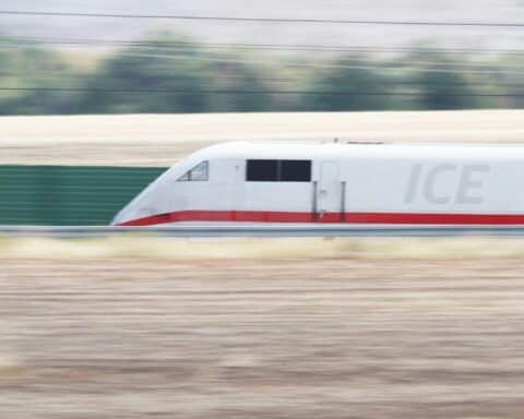 Ein moderner ICE-Zug fährt durch eine Landschaft, symbolisiert Reisewelle und Infrastrukturmodernisierung.